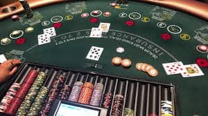 Tampilan studio Three Card Poker rajajp188 dengan dealer langsung dan kartu di meja